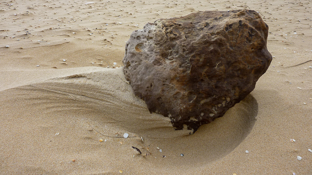 wind-swept-sand-around-rock-beach